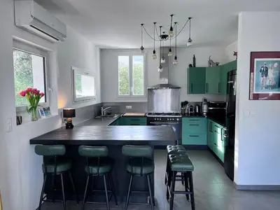 a kitchen with green cabinets and a large island with bar stools at Belle maison 4 chambres proche du centre ville et des plages in Ajaccio