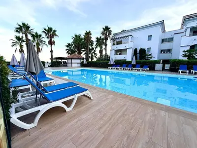 a swimming pool with chairs and umbrellas next to a building at Appartement avec piscine en Costa Verde in San-Nicolao