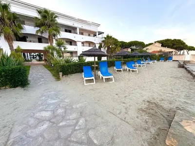 a row of blue chairs and umbrellas on a beach at Appartement avec piscine en Costa Verde in San-Nicolao