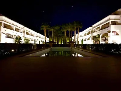 a large building with a pond in front of it at night at Appartement avec piscine en Costa Verde in San-Nicolao