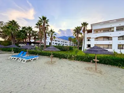 a beach with chairs and umbrellas and a building at Appartement avec piscine en Costa Verde in San-Nicolao