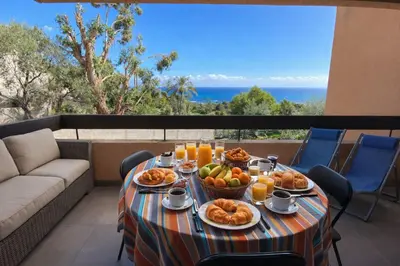 a table with food on a balcony with a view of the ocean at Le Scudo in Ajaccio