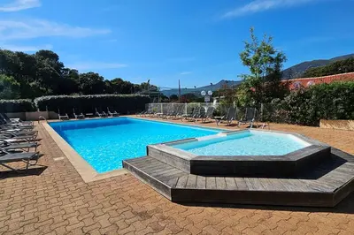a large swimming pool with chairs and a swimming poolvisor at Entre mer, piscine et maquis, T2 avec panorama in Propriano