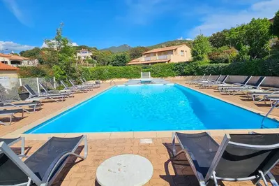 a large swimming pool with chairs and a table at Entre mer, piscine et maquis, T2 avec panorama in Propriano