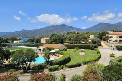 a resort with a swimming pool and mountains in the background at Entre mer, piscine et maquis, T2 avec panorama in Propriano