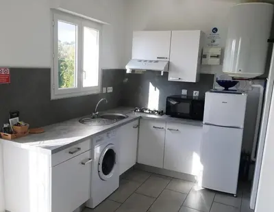 a kitchen with white cabinets and a sink and a washer at Charmants studios in Afa