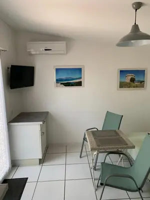 a living room with a table and chairs and a television at Charmants studios in Afa