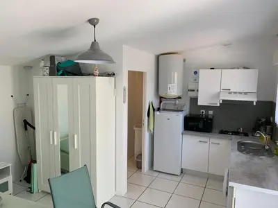 a kitchen with white cabinets and a white refrigerator at Charmants studios in Afa