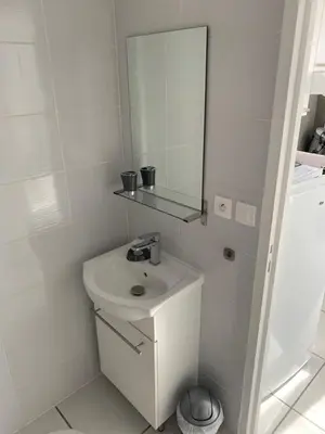 a white bathroom with a sink and a mirror at Charmants studios in Afa