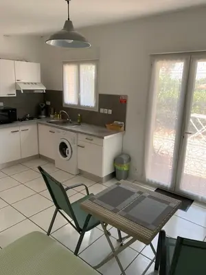 a kitchen with a table and chairs in a kitchen at Charmants studios in Afa