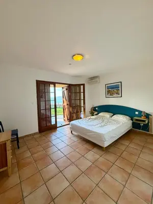 a bedroom with a bed and a tiled floor at Villa en pierre Vue imprenable sur le Golfe in Propriano