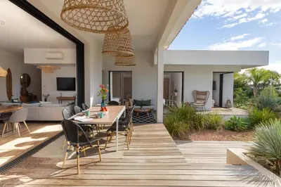 a dining room and living room with a table and chairs at Villa MIASULI, Domaine privé, Piscine chauffée, À 10 min de la plage in Sainte-Lucie de Porto-Vecchio
