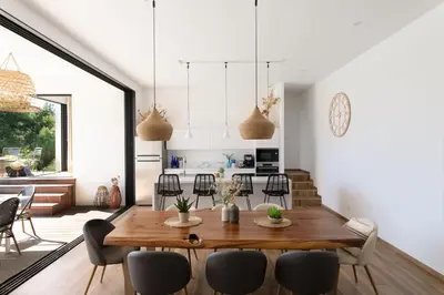 a kitchen and dining room with a wooden table and chairs at Villa MIASULI, Domaine privé, Piscine chauffée, À 10 min de la plage in Sainte-Lucie de Porto-Vecchio