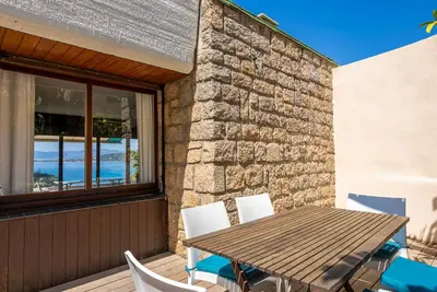 a wooden table and chairs on a porch with a table and chairsktop at PERLA DI VERGHIA Soleil et détente en Corse - Vue mer & plage à pied Villa 5 Chambres Grand Confort in Coti-Chiavari