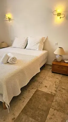a bedroom with a large white bed and a night stand at Villa Pinarello, Piscine et Mer in Zonza