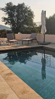 two chairs and an umbrella next to a swimming pool at Villa Pinarello, Piscine et Mer in Zonza