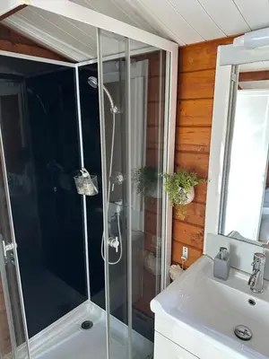 a shower with a glass door next to a sink at Chalet La Doulou Calme, Vue mer et jardin in Coti-Chiavari