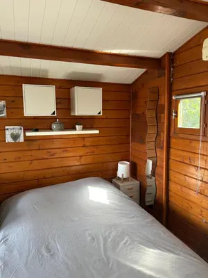 a bedroom with a bed in a wooden cabin at Chalet La Doulou Calme, Vue mer et jardin in Coti-Chiavari
