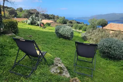two chairs sitting on the grass in a field at Mini villa vue mer et wifi dans petite résidence avec piscine chauffée in Serra-di-Ferro