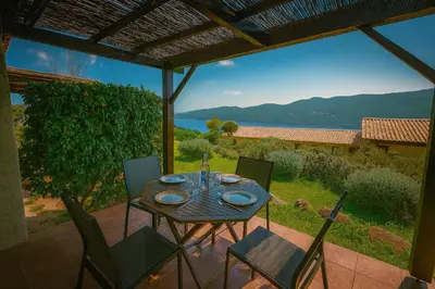 a table and chairs on a patio with a view at Mini villa vue mer et wifi dans petite résidence avec piscine chauffée in Serra-di-Ferro