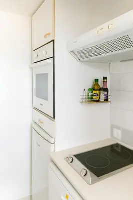 a white kitchen with a stove top oven next to a refrigerator at Mini villa vue mer et wifi dans petite résidence avec piscine chauffée in Serra-di-Ferro