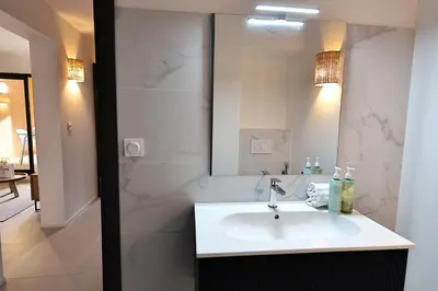 a white bathroom with a sink and a mirror at Cala di Sole - T2 Cabine, Piscine & Plage in Pianottoli-Caldarello