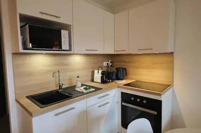 a kitchen with white cabinets and a sink and a microwave at Cala di Sole - T2 Cabine, Piscine & Plage in Pianottoli-Caldarello