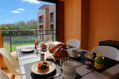 a table with food on it with a view of a balcony at Cala di Sole - T2 Cabine, Piscine & Plage in Pianottoli-Caldarello