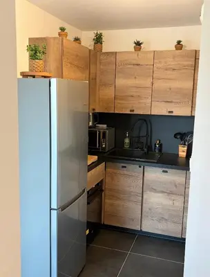 a kitchen with wooden cabinets and a stainless steel refrigerator at L'Onda Serena - 4 couchages à 5 min de la plage in Ajaccio