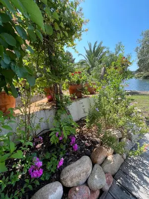 a garden with flowers and rocks next to the water at San Ciprianu-Lecci House, seaside, beach 2'' in Lecci