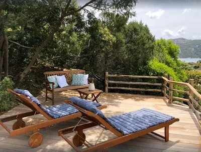 a deck with two lounge chairs and a table at Villa Santa Giulia, vue mer, plage à pieds in Porto-Vecchio