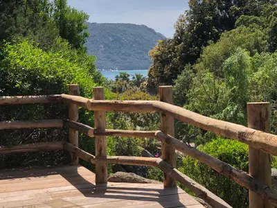 a wooden boardwalk with a view of the water at Villa Santa Giulia, vue mer, plage à pieds in Porto-Vecchio