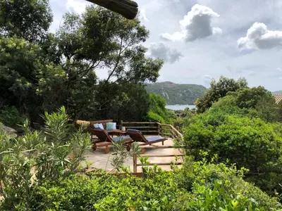a patio with chairs and a table in a garden at Villa Santa Giulia, vue mer, plage à pieds in Porto-Vecchio