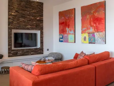 an orange couch in a living room with a tv at Exclusive holiday home with pool in Porto-Vecchio