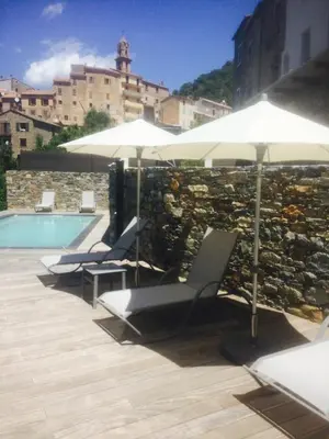 a row of chairs and umbrellas next to a stone wall at Saint Christophe in Omessa