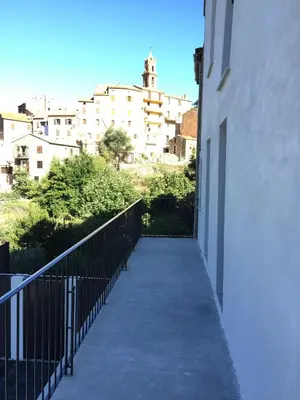 a walkway leading to a building with buildings in the background at Saint Christophe in Omessa