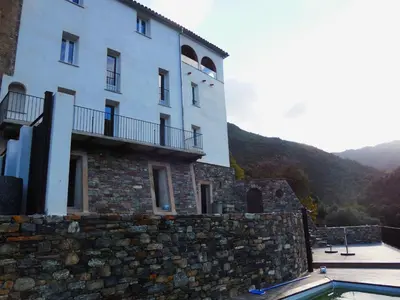 a building with a stone wall next to a pool at Saint Christophe in Omessa
