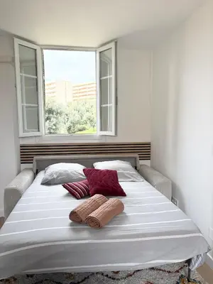 a white bed with two pillows and a window at Bienvenue chez vous ! in Ajaccio