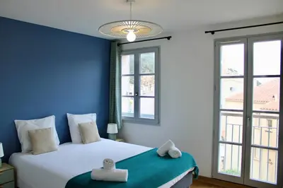 a bedroom with a bed with blue walls and windows at Les Hauts du Port - T2 Moderne et chaleureux in Bonifacio