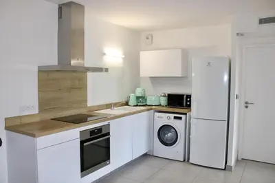 a kitchen with a white refrigerator and a couch at Les Hauts du Port - T2 Moderne et chaleureux in Bonifacio