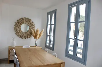 a dining room with a wooden table and a mirror at Les Hauts du Port - T2 Moderne et chaleureux in Bonifacio