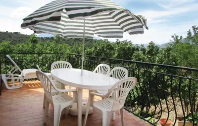 a table and chairs on a balcony with an umbrella at Gorgeous Home In Valle Di Rostino in Valle-di-Rostino