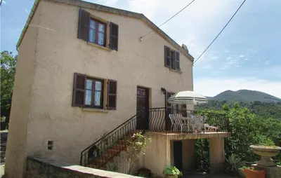 a house with a balcony with a table and an umbrella at Gorgeous Home In Valle Di Rostino in Valle-di-Rostino