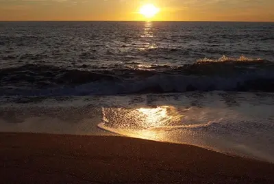 a sunset over the ocean with a beach with waves at A Casa Nèra in Porto Pollo