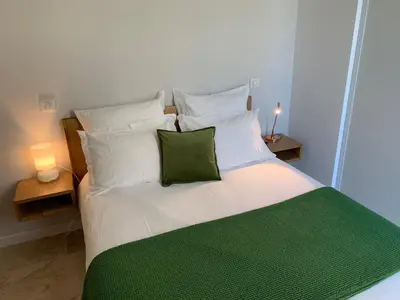 a bed with white pillows and a green blanket at A Casa Nèra in Porto Pollo