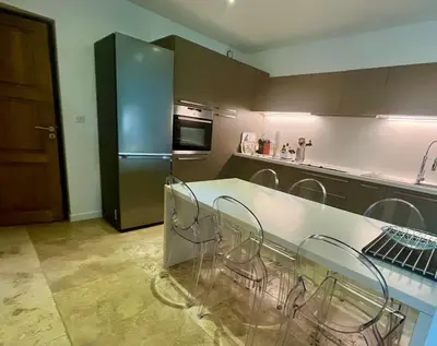a kitchen with a counter with chairs and a refrigerator at A Casa Nèra in Porto Pollo