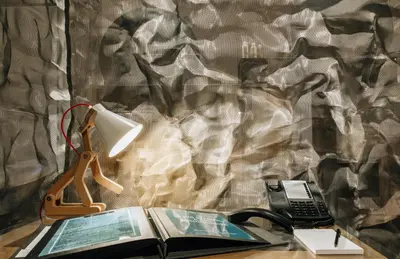 a desk with a lamp and a book and a phone at Citta di Lume Suites & Lofts in Porto-Vecchio