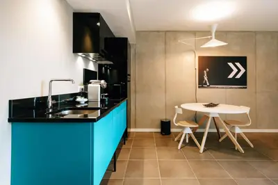 a kitchen with blue cabinets and a white table at Citta di Lume Suites & Lofts in Porto-Vecchio