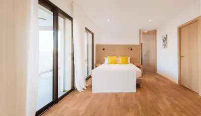 a bedroom with a white bed and large windows at Citta di Lume Suites & Lofts in Porto-Vecchio