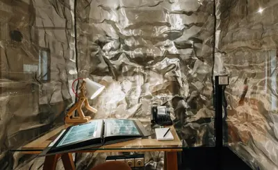 a stone wall with a table with a book and a phone at Citta di Lume Suites & Lofts in Porto-Vecchio